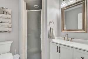 A bathroom with white cabinets and a shower stall.