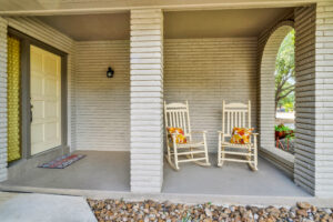 Two rocking chairs on a porch with pillows.