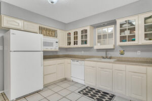A kitchen with white cabinets and tile floors.